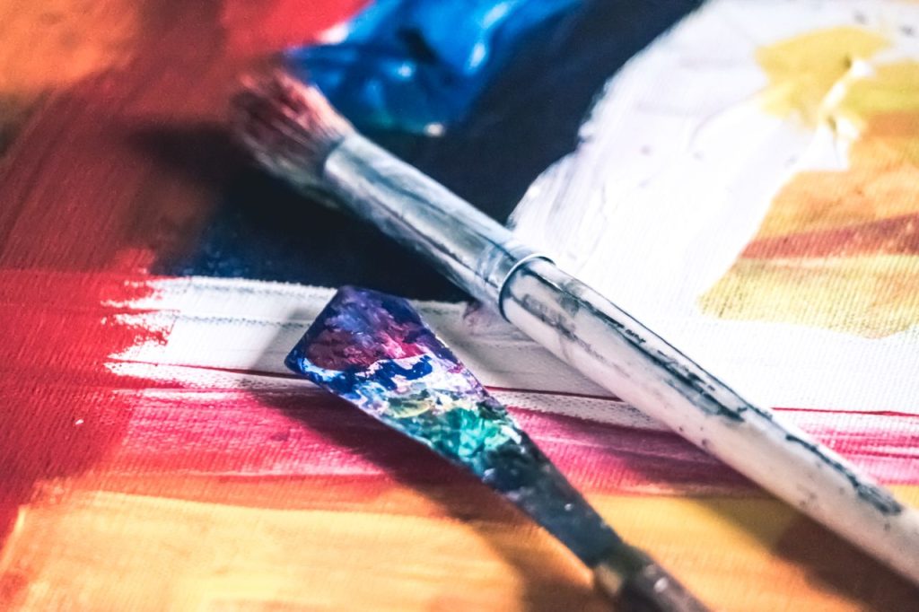 Close-up of colorful paintbrushes on a vibrant canvas, showcasing creativity and artistic expression.