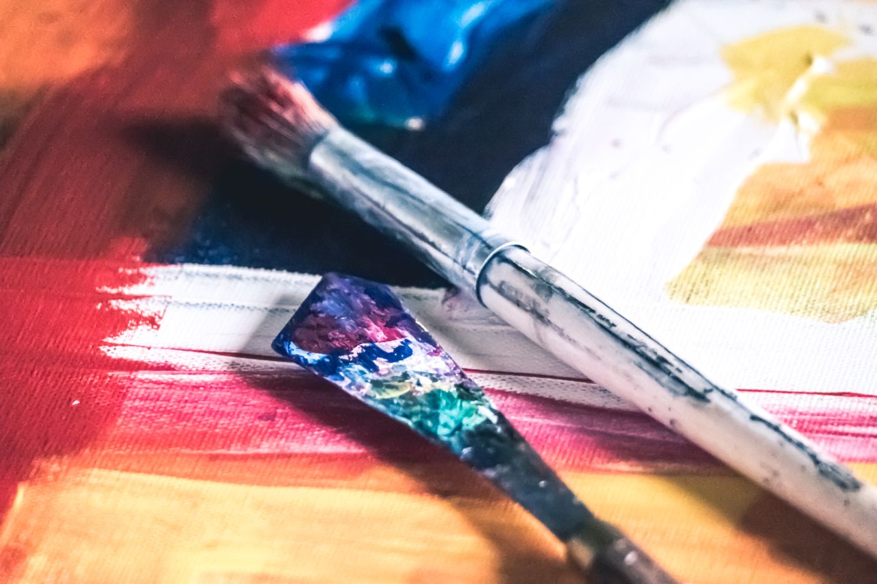 Close-up of colorful paintbrushes on a vibrant canvas, showcasing creativity and artistic expression.